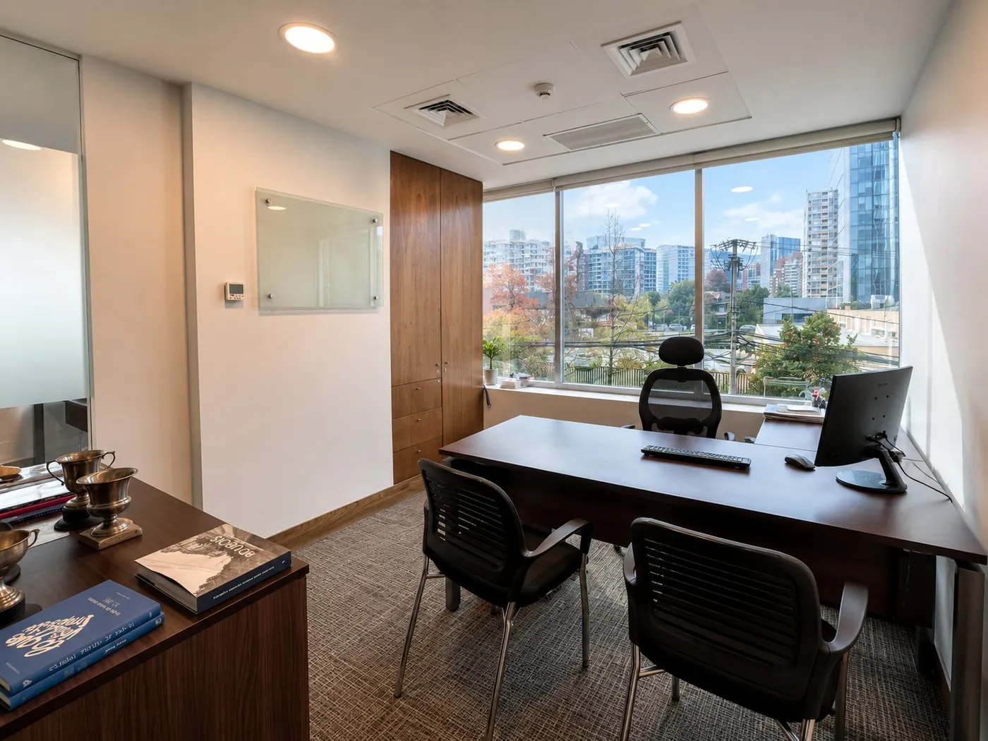 Oficina privada con escritorio, sillas de visita y vista a la ciudad